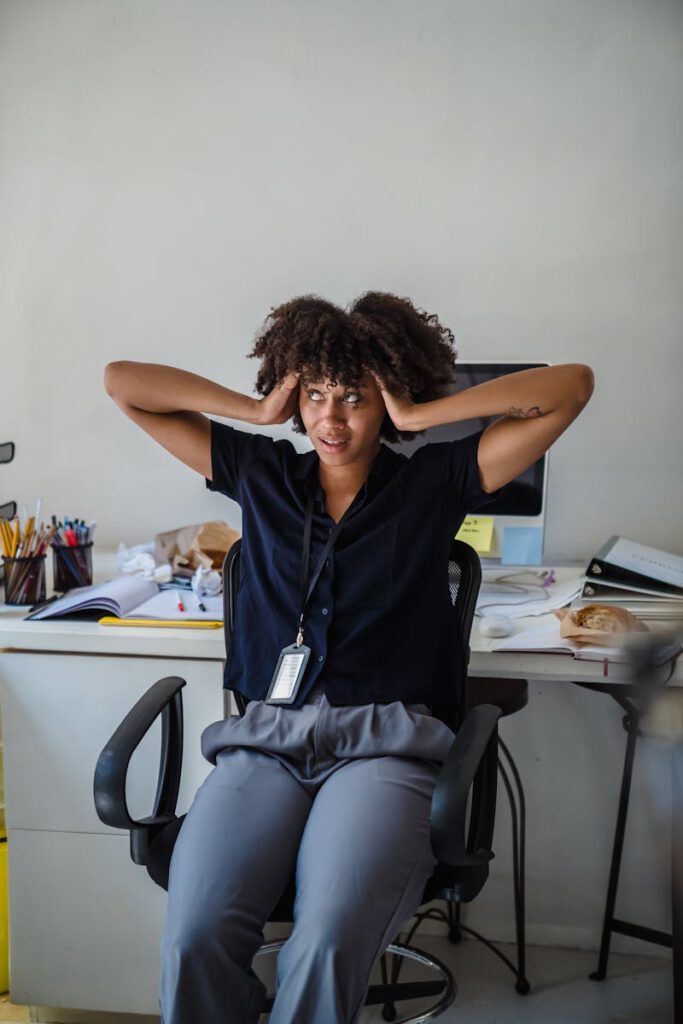 Businesswoman experiencing stress at her desk in a busy office environment.